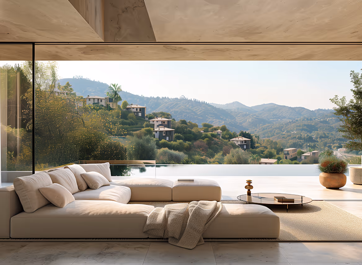 Modern living room with beige sectional sofa and large glass window overlooking hillside houses and mountains.